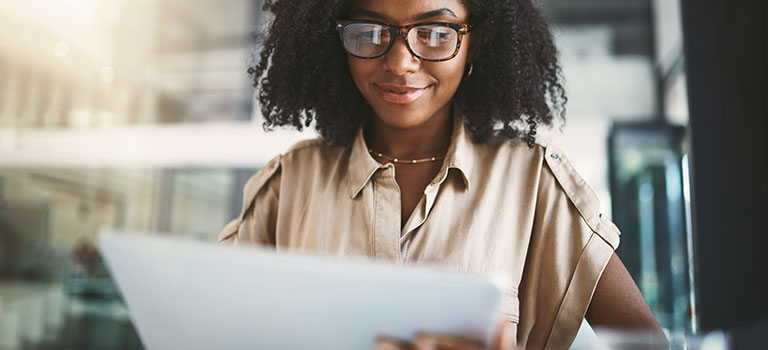 Smiling, smart young professional wearing business attire in office environment looking confidently at a sheet of paper