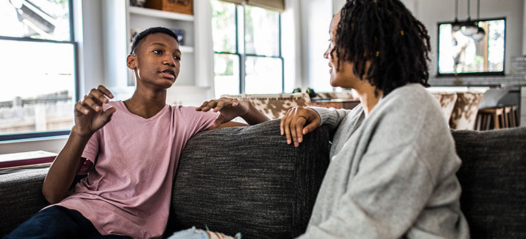 Mother and teen son having a conversation on the living room sofa